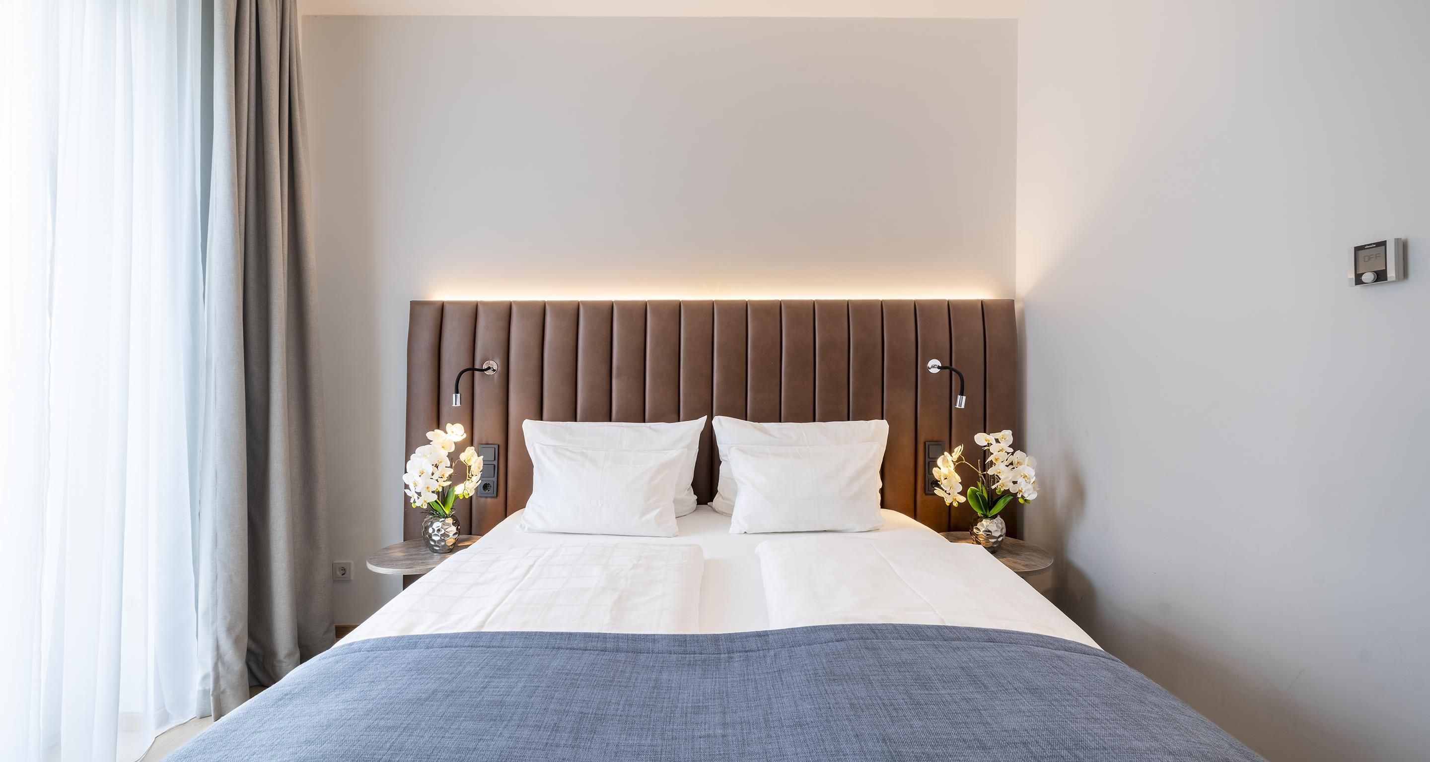 A hotel room with a bed, nightstands, and a headboard.