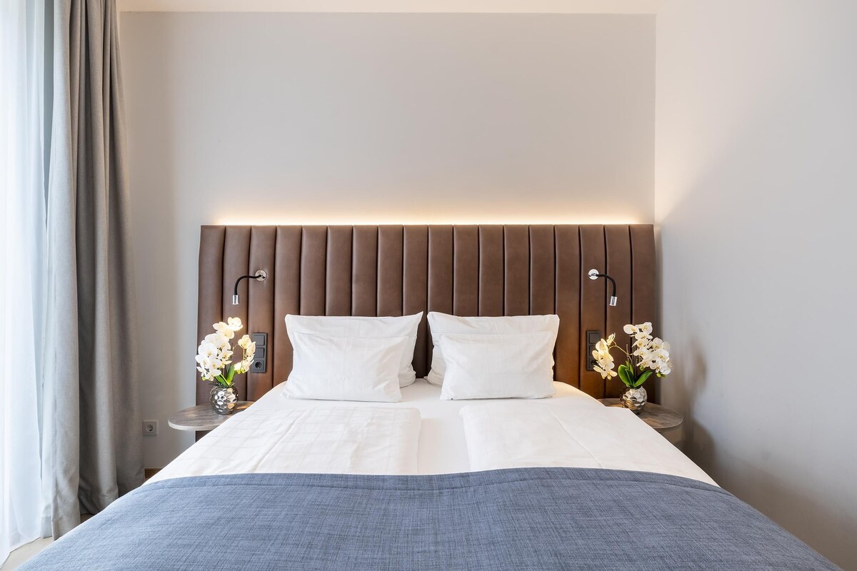 A hotel room with a bed, nightstands, and a headboard.