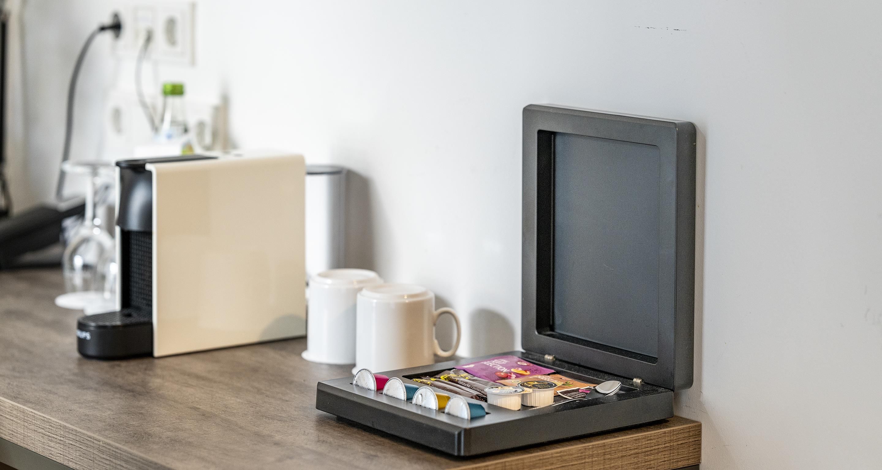 A coffee machine and a tray with various food items on a wooden surface.