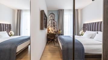 Una habitación de hotel con dos camas, un escritorio y vistas a un edificio a través de una ventana.