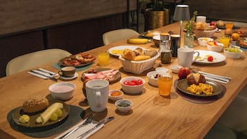 Un bufé de desayuno con diversos platos, como huevos, pasteles y frutas.