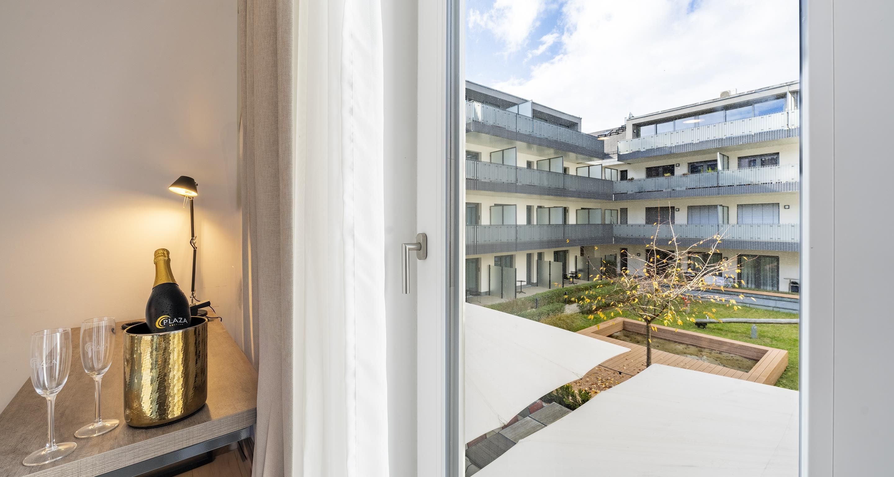 A modern apartment with a balcony overlooking a courtyard and a building.