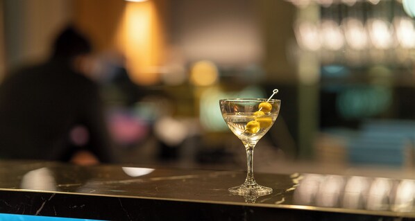 A martini glass with lemon slices on a reflective surface.