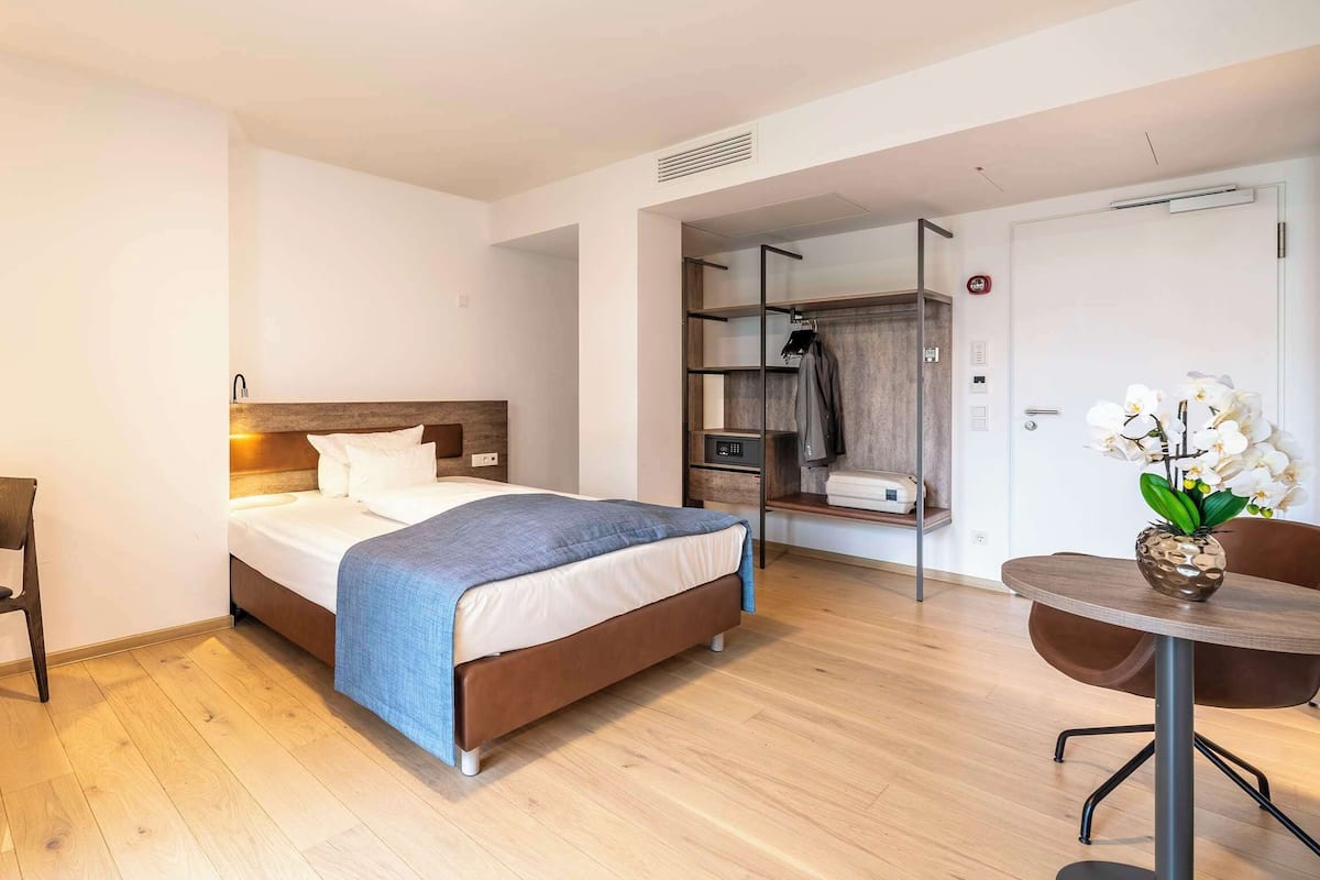 Una habitación de hotel con cama, escritorio, silla, mesa y armario.