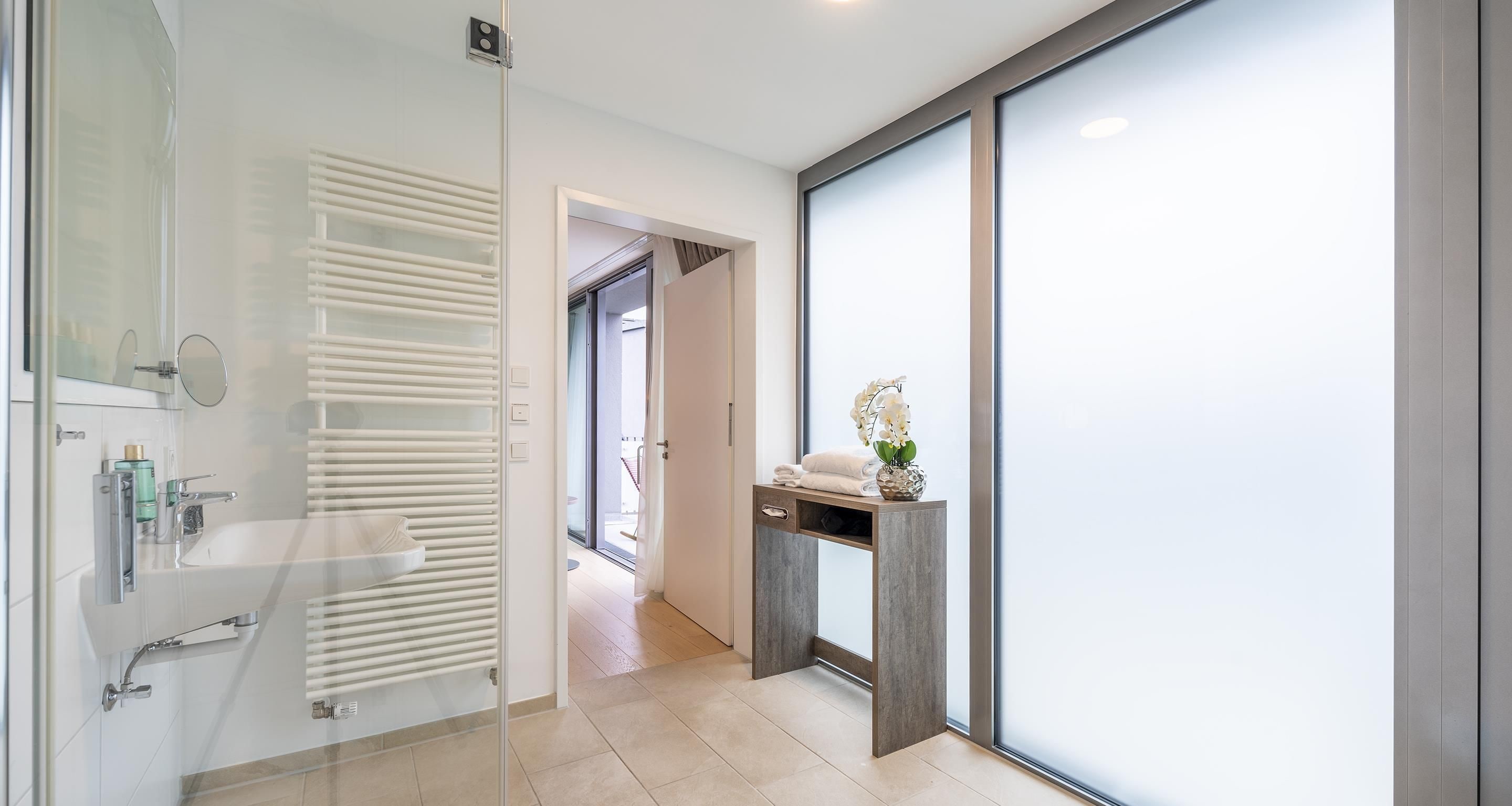 A modern bathroom with a glass shower enclosure, a white sink, and a vanity with a mirror.