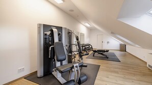 A modern gym with various exercise machines, a bench, and a mirror on the wall. - Aiden by Best Western Biberach (Biberach an der Riss)