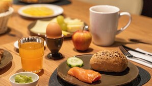 A breakfast setting with a plate of food, a glass of orange juice, a cup, and a small bowl of guacamole. - Aiden by Best Western Biberach (Biberach an der Riss)