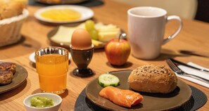 A breakfast setting with a plate of food, a glass of orange juice, a cup, and a small bowl of guacamole. - Aiden by Best Western Biberach (Biberach an der Riss)