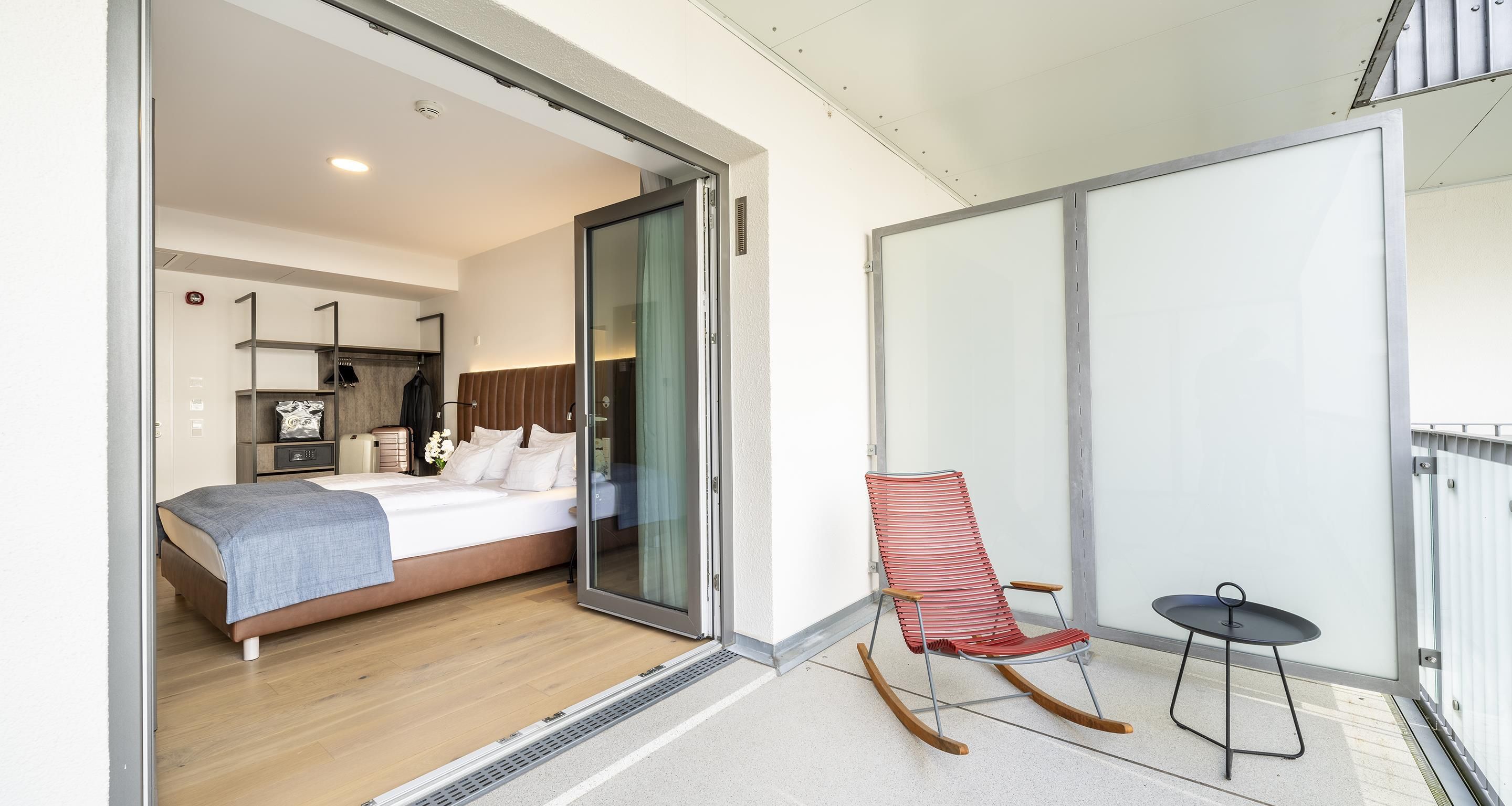 A modern hotel room with a bed, a chair, and a small table.