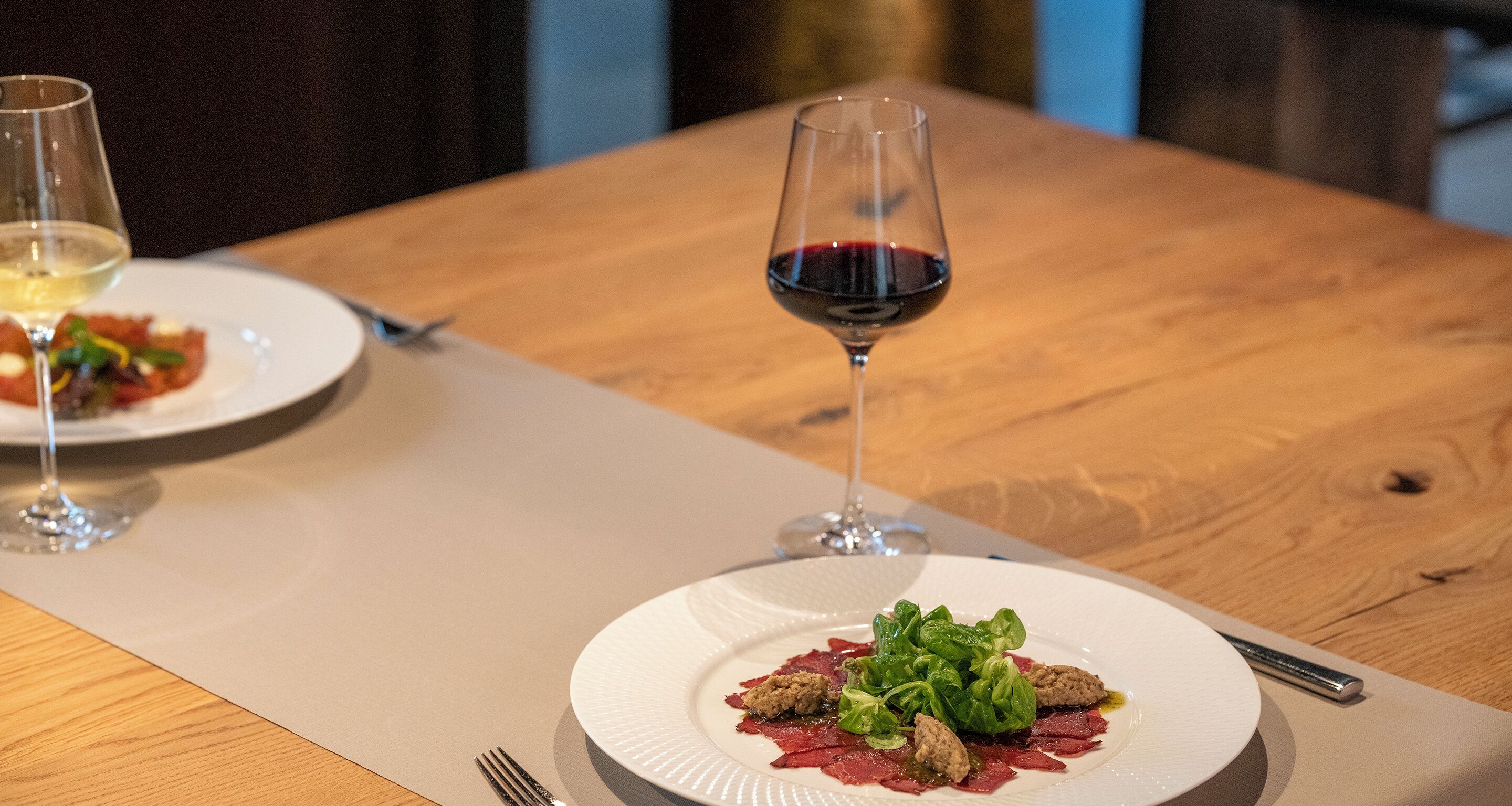 A dining table with a plate of food and a glass of red wine.