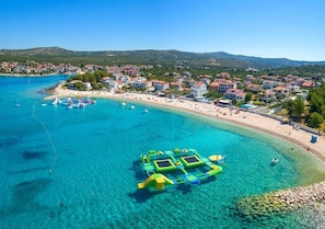 A coastal town with clear blue waters, a sandy beach, and a floating structure.