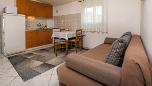 Eine kleine Küche mit Holzschränken, einem Esstisch mit Stühlen und einem Sofa mit Kissen.