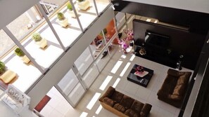 A spacious living area with a sofa, a coffee table, and a TV. There are potted plants and a fireplace. - Gaúcho Hotel (Tapejara)