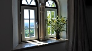 Ein Fenster mit Blick auf Grün und eine Vase mit Blumen.
