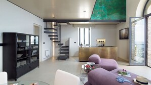 Un espacio de estar moderno con un mueble negro, un sofá morado y una mesa de centro de cristal.
