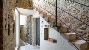Una escalera de piedra con barandilla de metal que lleva a una puerta con placa decorativa.