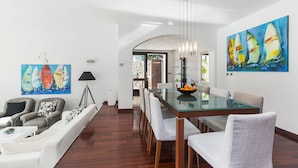 A modern dining area with a glass table and chairs, a white sofa, and two paintings on the walls. - Villa Andrea (Punat)