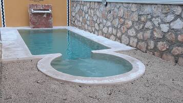 Una piscina con un muro de piedra y un cartel que indica 'Nh Nicol-Haa Hotel'.