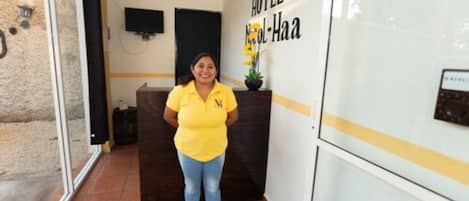 Zona de recepción con un cartel que dice "HOTEL Nobil-Haa", un mostrador de recepción y un televisor montado en la pared.