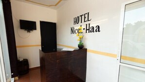 A reception desk with a sign reading "HOTEL Nice-Haa" and a television mounted on the wall. - Nicol-Haa (Izamal)