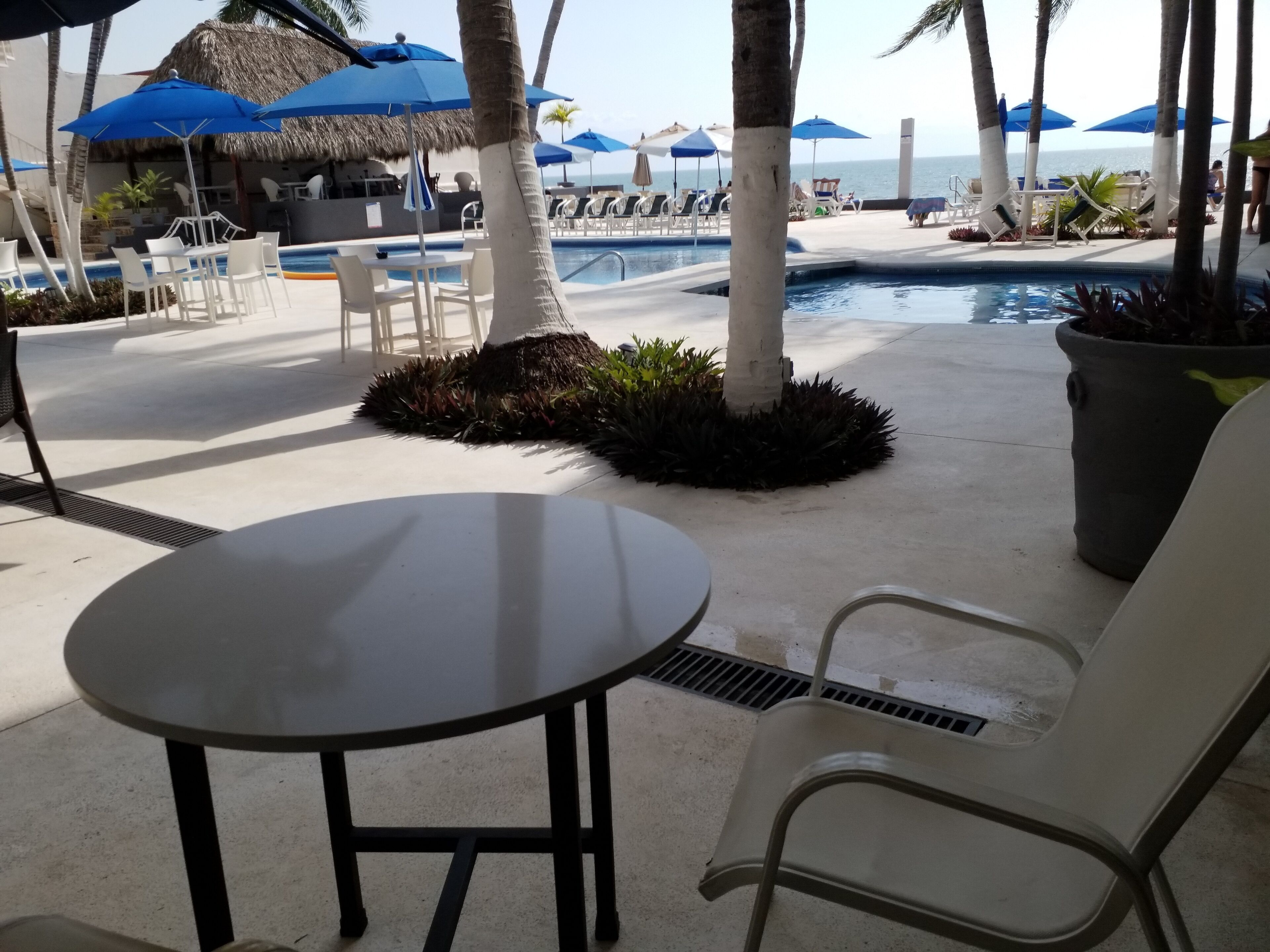 Un espace aménagé au bord de la piscine, avec des chaises longues, des parasols et une table.