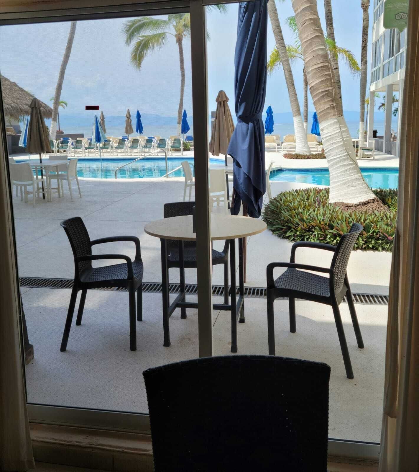 A view of a poolside area with lounge chairs and umbrellas, a table, and a chair.