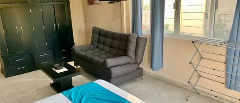 A room with a bed, a sofa, a TV, a wardrobe, and a window with curtains.