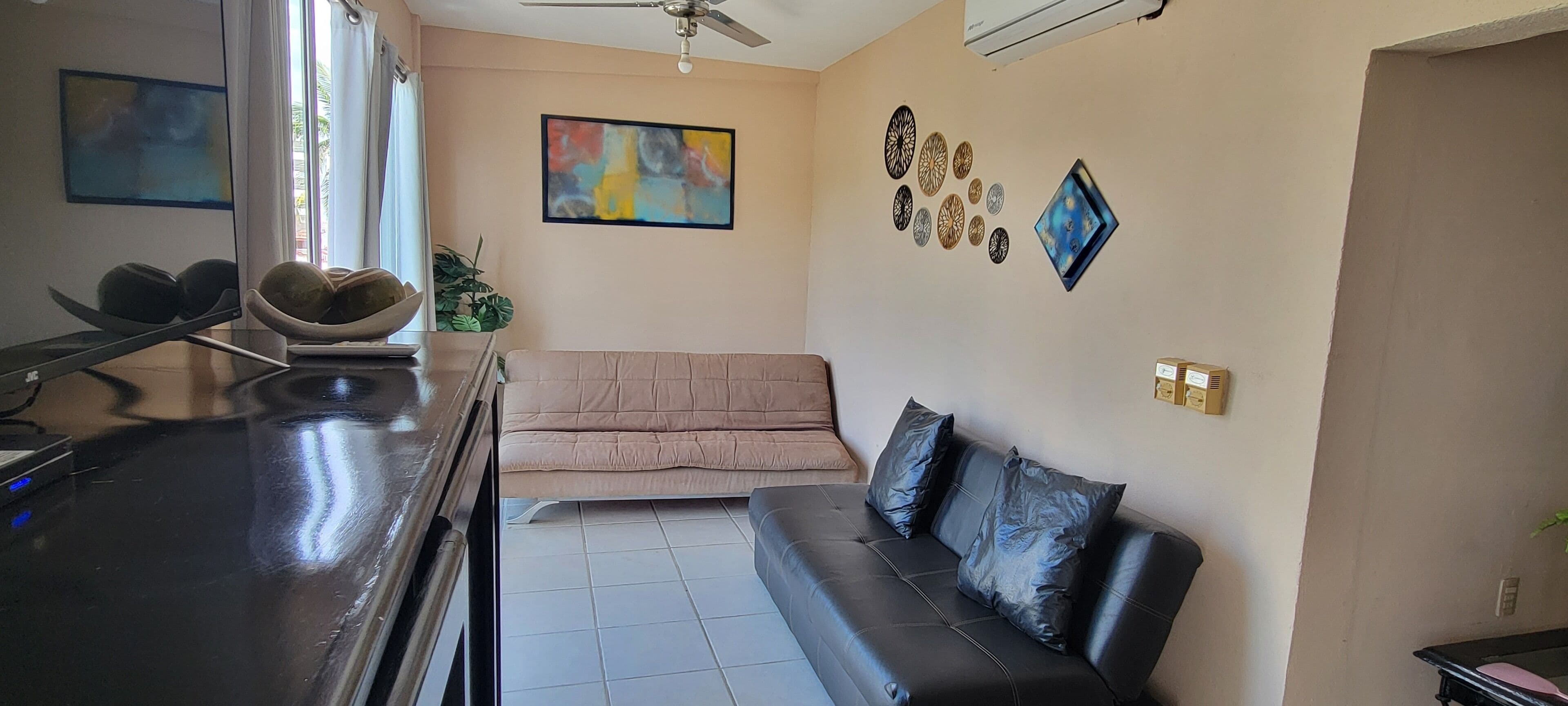 A living room with a sofa, a coffee table, a TV, and wall decorations.