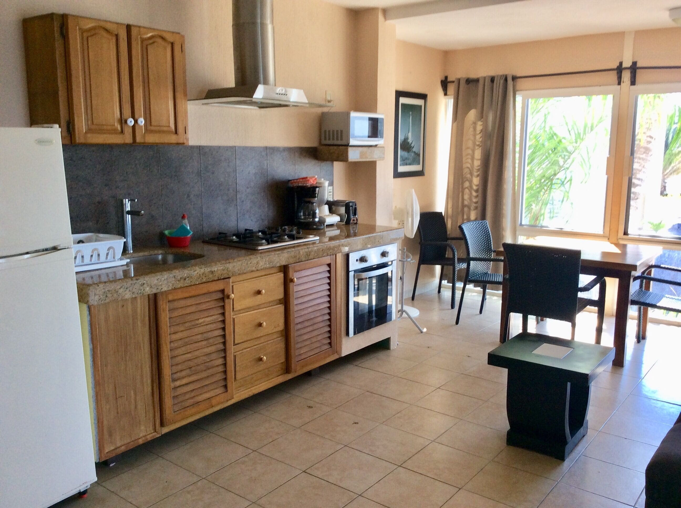 A kitchen with wooden cabinets, a microwave, a stove, and a dining area with chairs and a table.