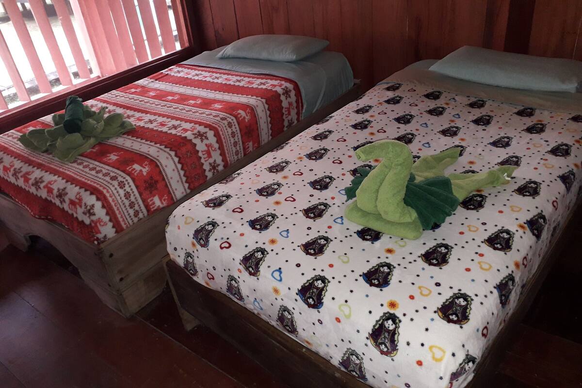 Two wooden beds with red and white patterned bedding, each with a green plush toy.