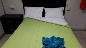 A bed with a green bedspread, white pillows, and a blue floral bedspread.