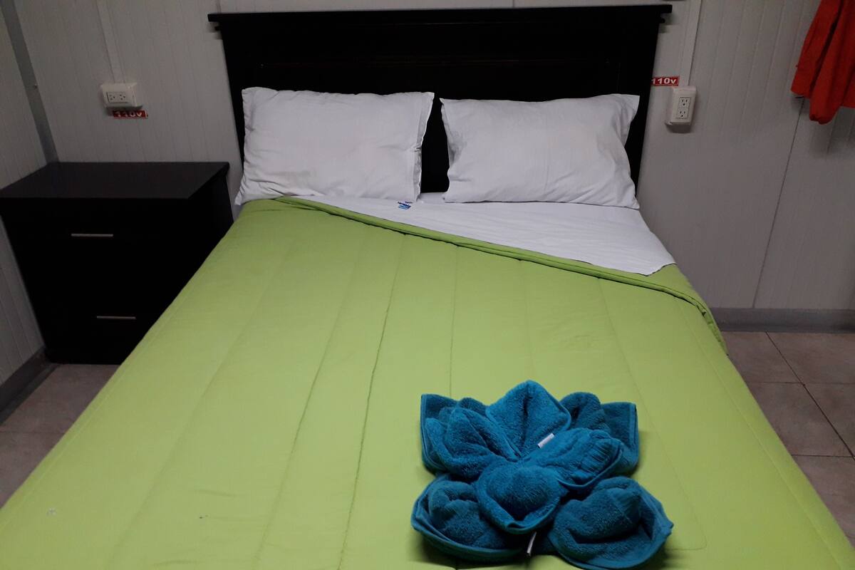 A bed with a green bedspread, white pillows, and a blue floral bedspread.