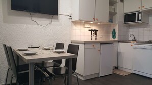Een kleine keuken met een eettafel voor vier personen, een magnetron en een vaatwasser.
