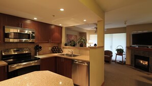A modern kitchen with stainless steel appliances, a granite countertop, and wooden cabinets. - Lagoons Condos by Whistler Retreats (Whistler)