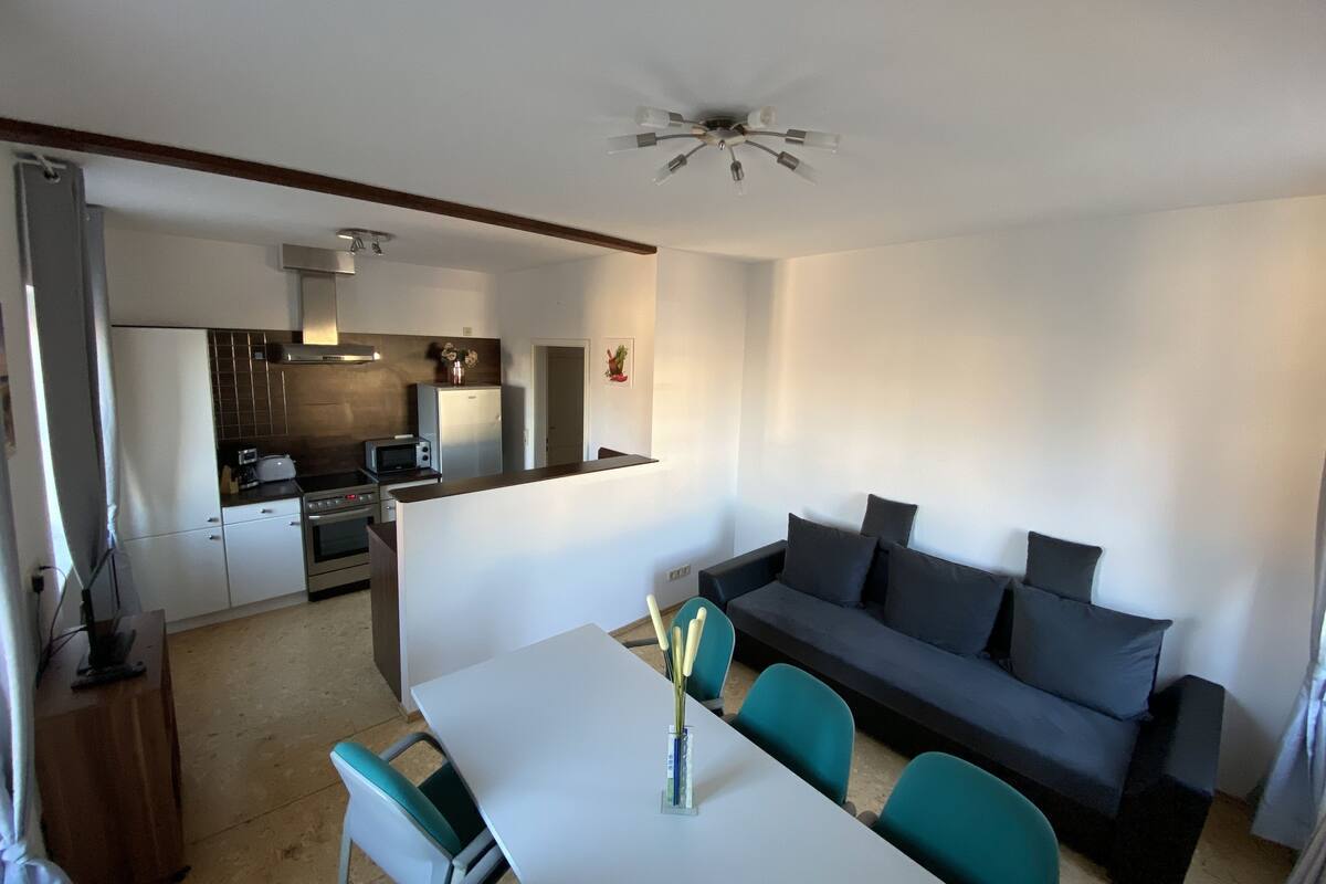A compact living space with a kitchenette, a dining area with a table and chairs, and a sofa.
