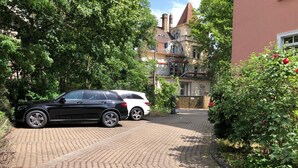 A paved driveway leading to a building with a brick facade and a red door.