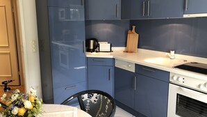 A modern kitchen with blue cabinets, a white countertop, and a built-in oven.