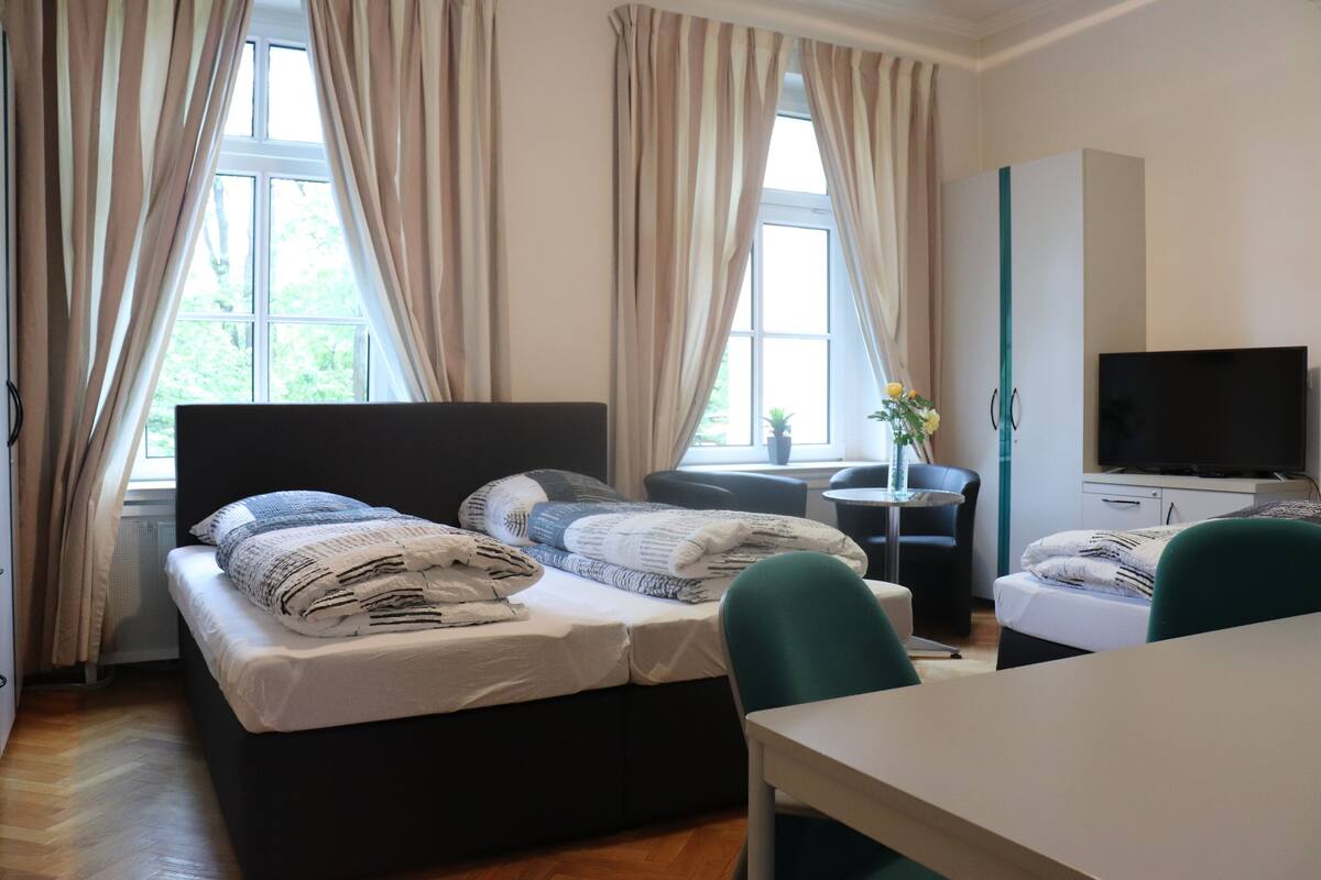 A hotel room with a bed, a desk, a TV, and curtains.