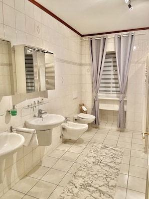Et badeværelse med to håndvaske, en bidet og et toilet.