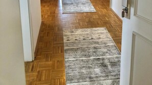 A hallway with wooden flooring, two rugs, and a door with a keypad lock.
