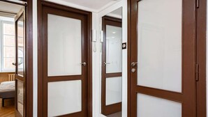 Un pasillo con puertas de madera y una cama al fondo.