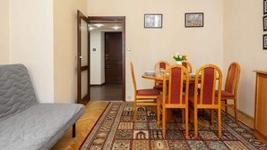 Una habitación acogedora con un sofá gris, una mesa de comedor con cuatro sillas y una alfombra estampada.
