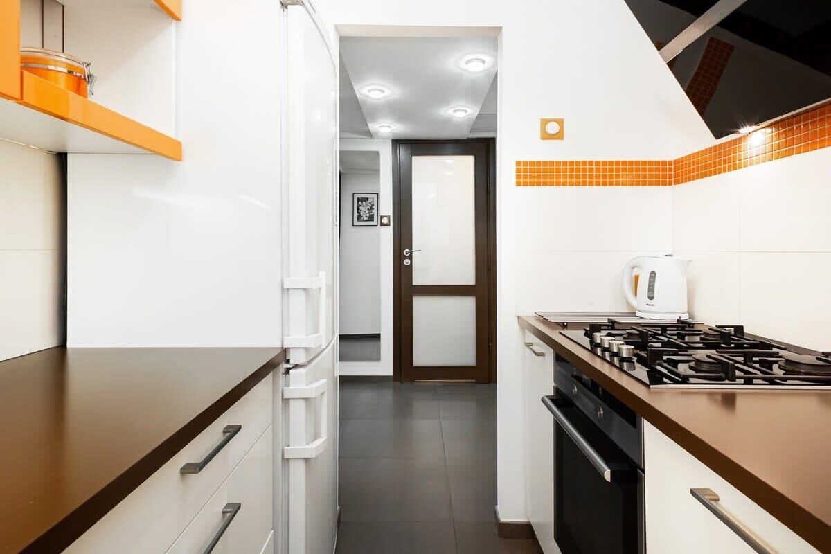 A compact kitchen with white cabinets, a brown countertop, a gas stove, and a coffee maker.