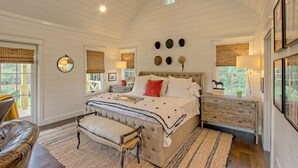 A spacious bedroom with a large bed, a wooden dresser, and a leather armchair.
