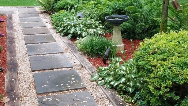 A garden pathway with stepping stones, surrounded by lush greenery and a wooden pergola. - Big house, big yard, close to everything in Mount Gretna! (Mt Gretna)
