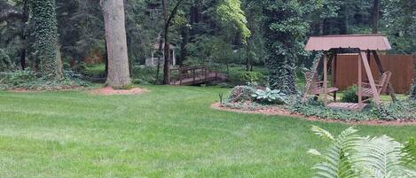 A well-maintained garden with a wooden playhouse, a gazebo, and a variety of trees and shrubs.