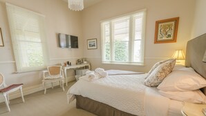 Een slaapkamer met een groot bed, een bureau, een stoel en een televisie.