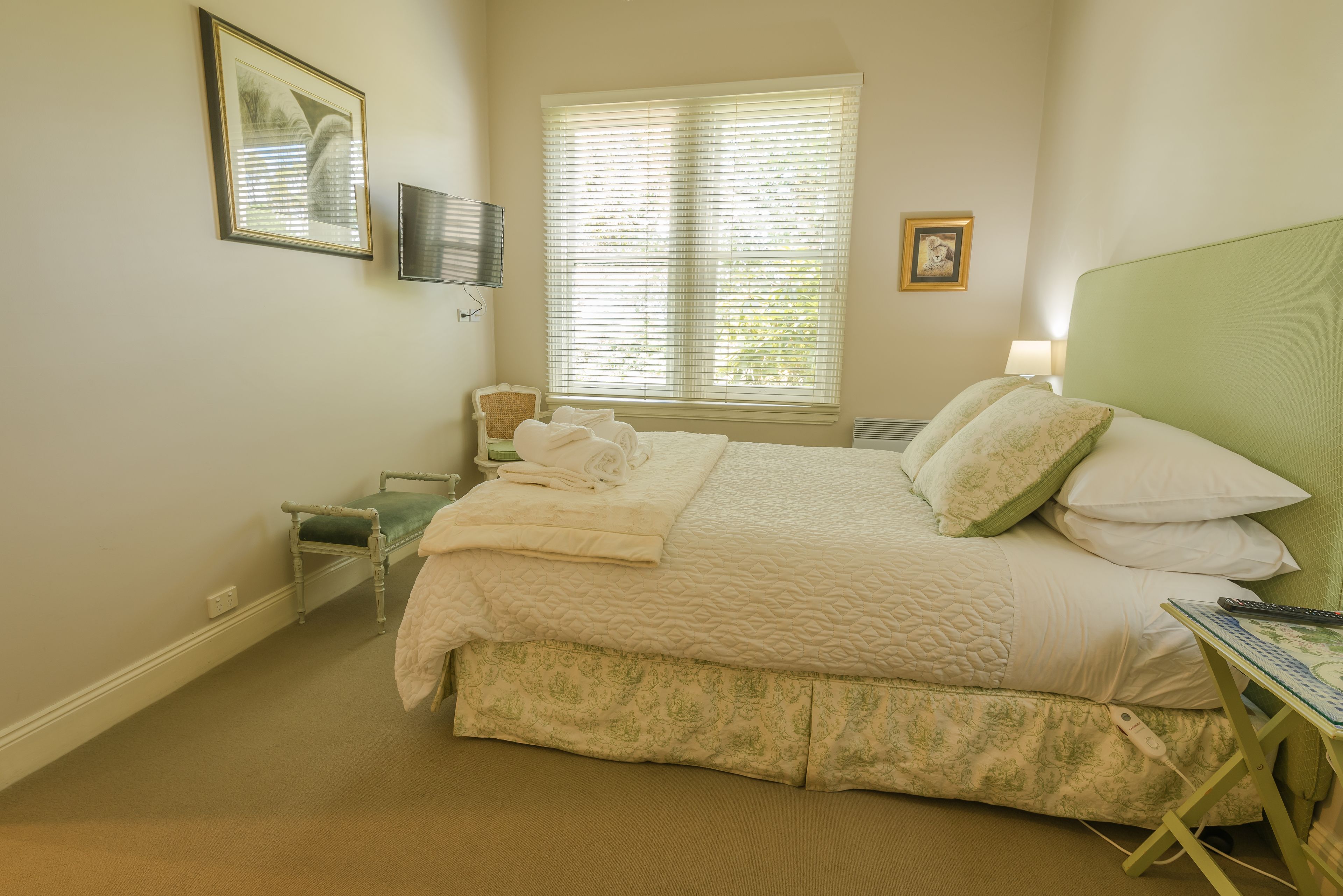 Une chambre bien rangée, avec un grand lit, une table de chevet et une chaise.