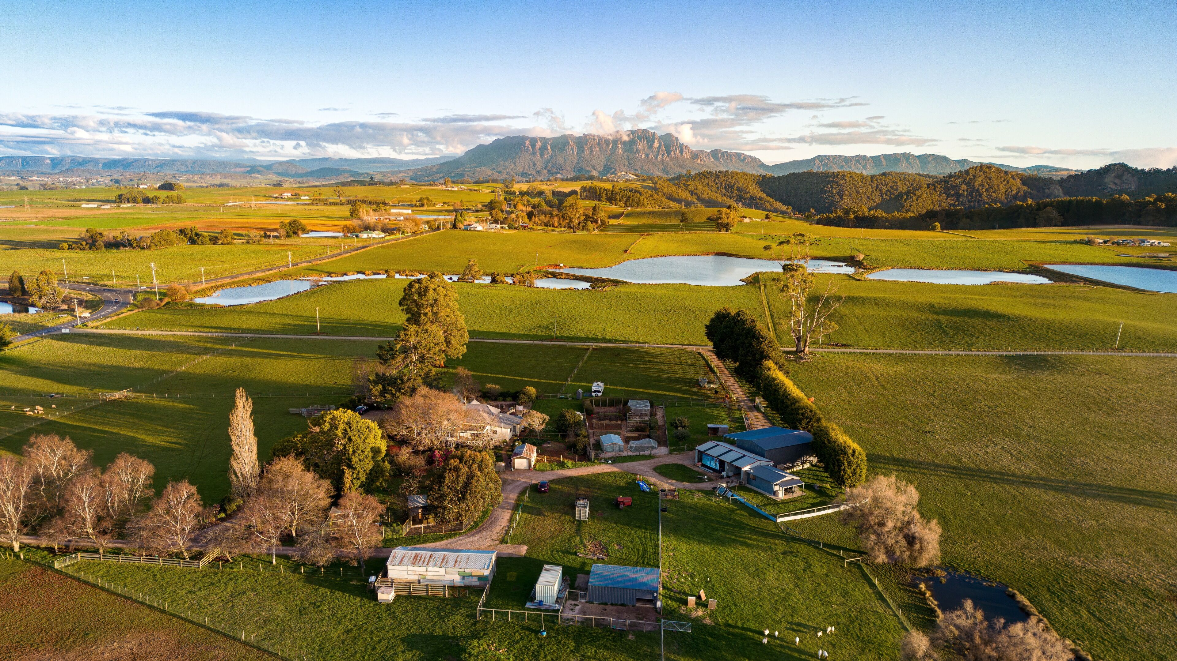 An aerial view of a rural property with fields, a small house, and a barn.