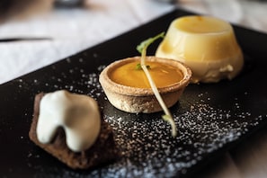 Un plato de postres con una tarta, un flan y un pastelito cubierto de crema.